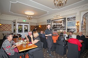 Un espace repas avec des tables, des chaises et un serveur qui apporte les boissons.