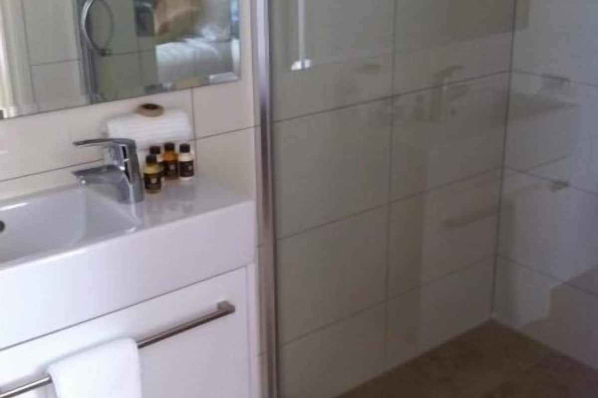 A modern bathroom with a glass shower enclosure, a white sink with a towel, and a mirror.