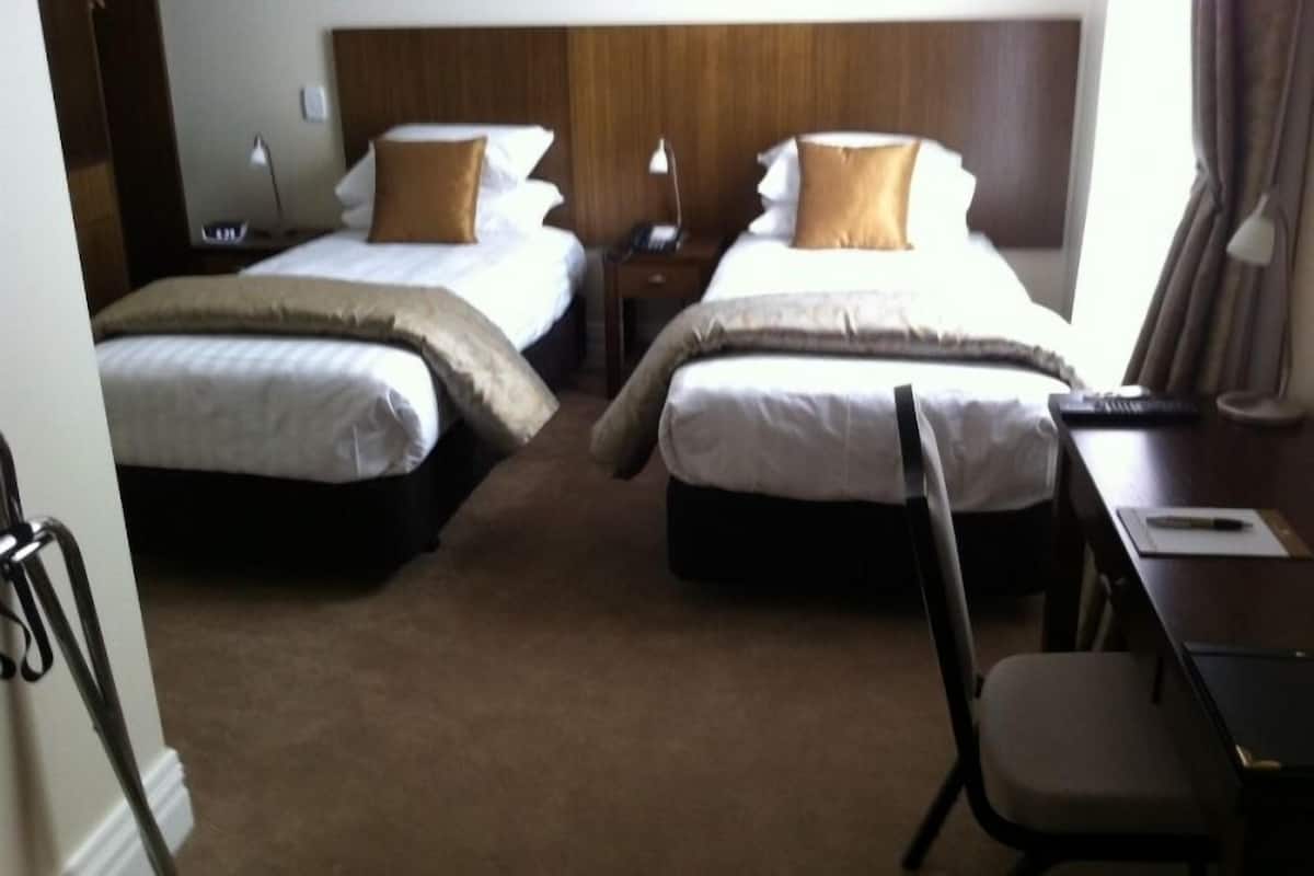 A hotel room with two beds, a desk, and a chair.