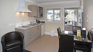 A compact kitchen with a microwave, sink, and a dining area with a table and chairs.
