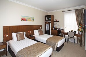Une chambre d’hôtel avec deux lits, un bureau, une chaise, une armoire et un tableau au mur.