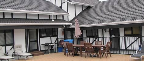 Ein Haus mit Swimmingpool, einer überdachten Terrasse mit Tisch und Stühlen sowie einer Treppe, die zum Obergeschoss führt.