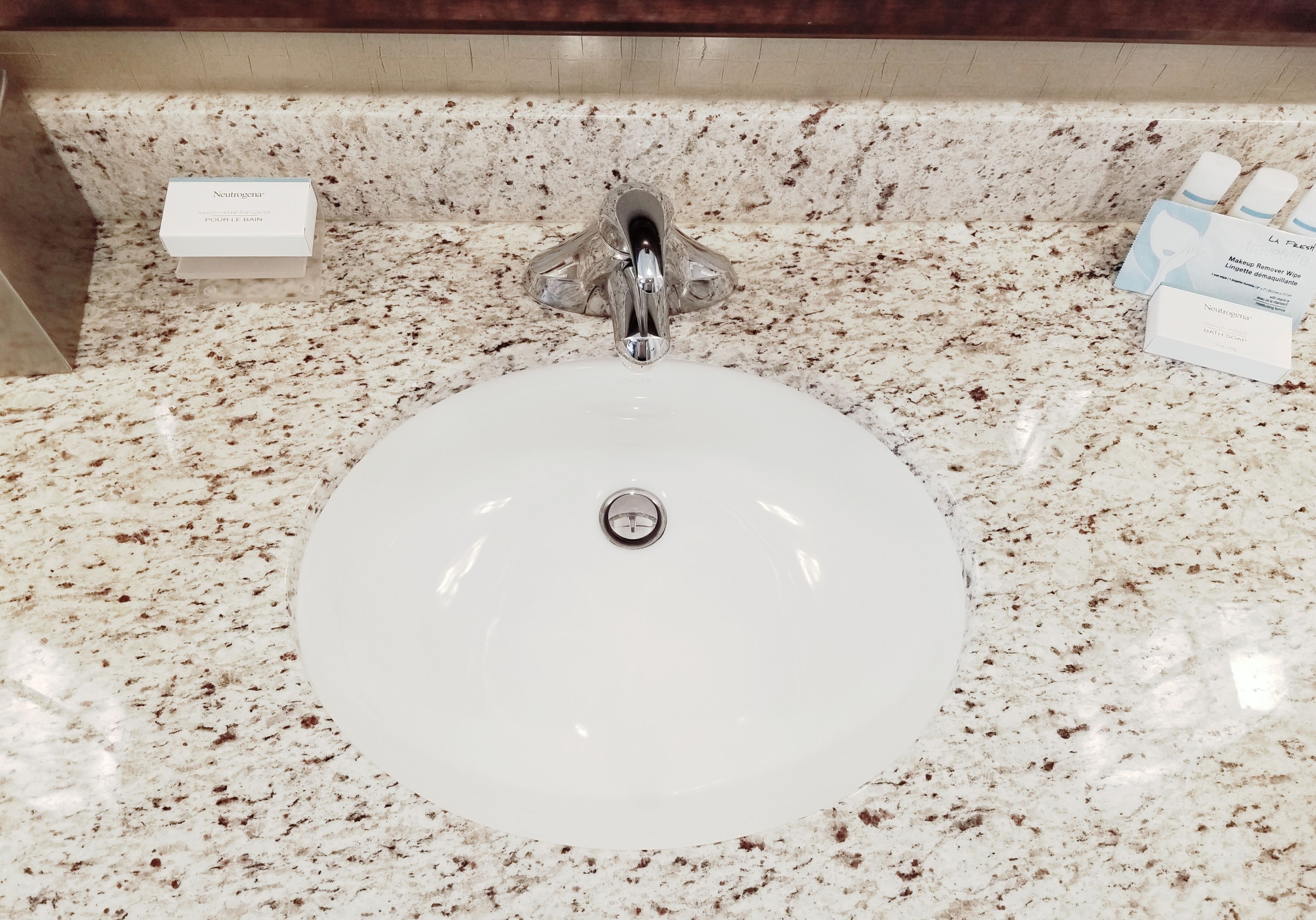 A bathroom sink with a marble countertop, a faucet, and Neutrogena products.