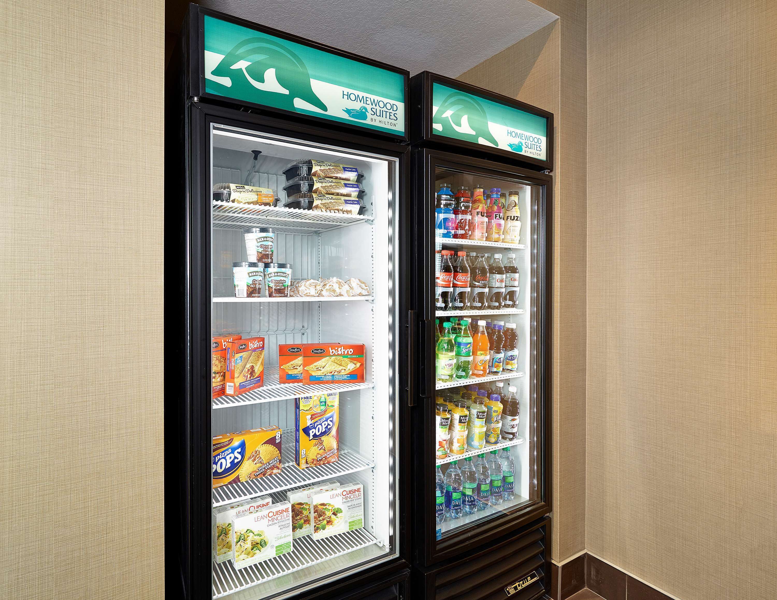 Deux vitrines réfrigérées dans le hall d’un hôtel, remplies de collations, de boissons et d’aliments surgelés.