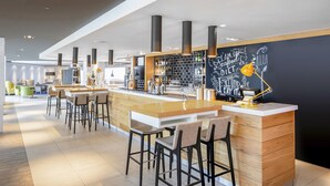 A modern bar area with high stools, a counter, and a chalkboard wall with motivational writing.