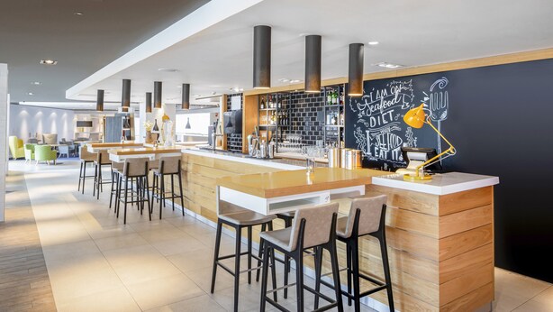 A modern bar area with high stools, a counter, and a chalkboard wall with motivational writing.