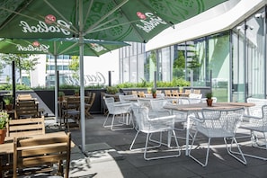 An outdoor seating area with tables and chairs, some with umbrellas, and potted plants. - Holiday Inn Amsterdam - Arena Towers by IHG (Amsterdam)