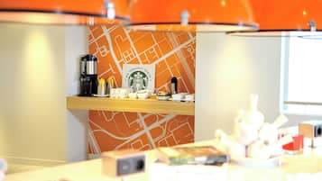 A modern interior with a wooden counter, a Starbucks sign, and orange lighting fixtures.