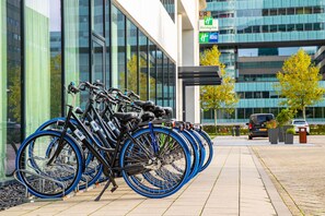 Une rangée de vélos est garée devant un immeuble doté de grandes fenêtres et d’une enseigne indiquant la présence d’un hôtel Holiday Inn Express.