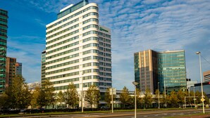 A modern hotel with a curved facade, multiple floors, and a glass exterior.