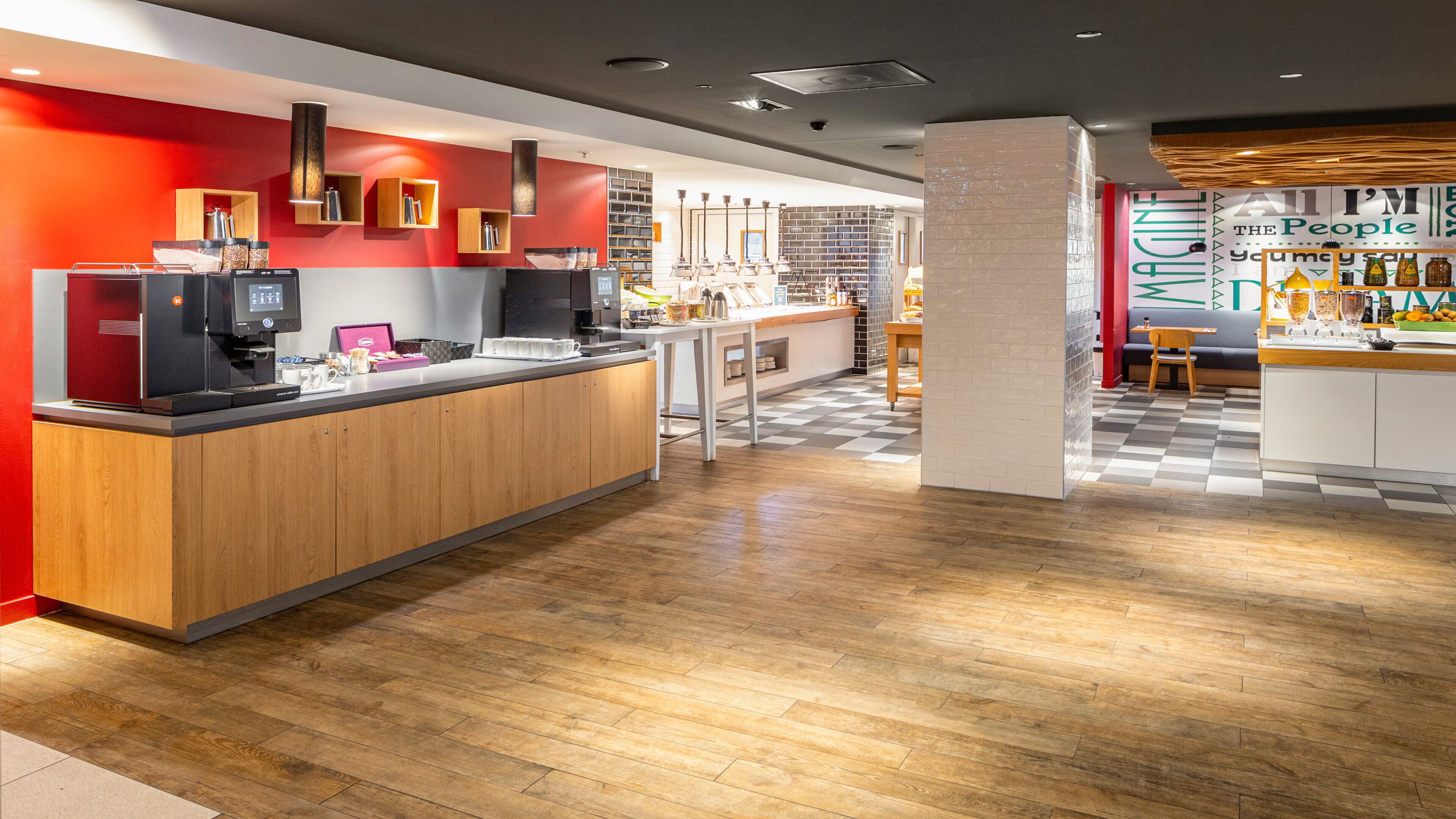 A modern kitchen area with wooden cabinets, a coffee machine, and a checkered floor.