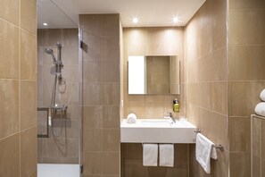 Une salle de bain moderne avec une douche, un lavabo et un miroir.