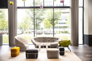A modern lounge area with a sofa, ottomans, and a coffee table. - Holiday Inn Amsterdam - Arena Towers by IHG (Amsterdam)