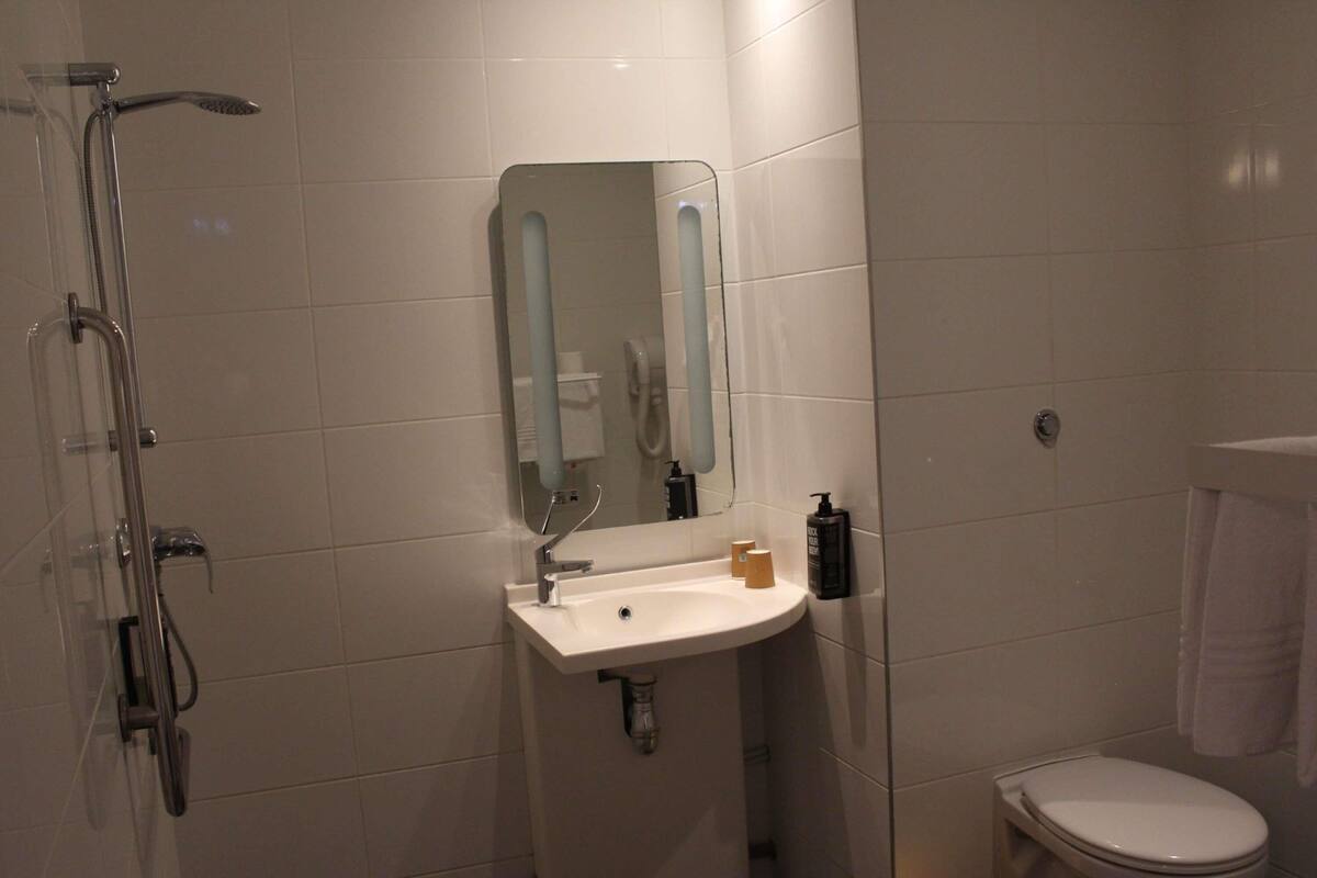 Une salle de bain équipée d’une douche, d’un lavabo, d’un miroir et de toilettes.