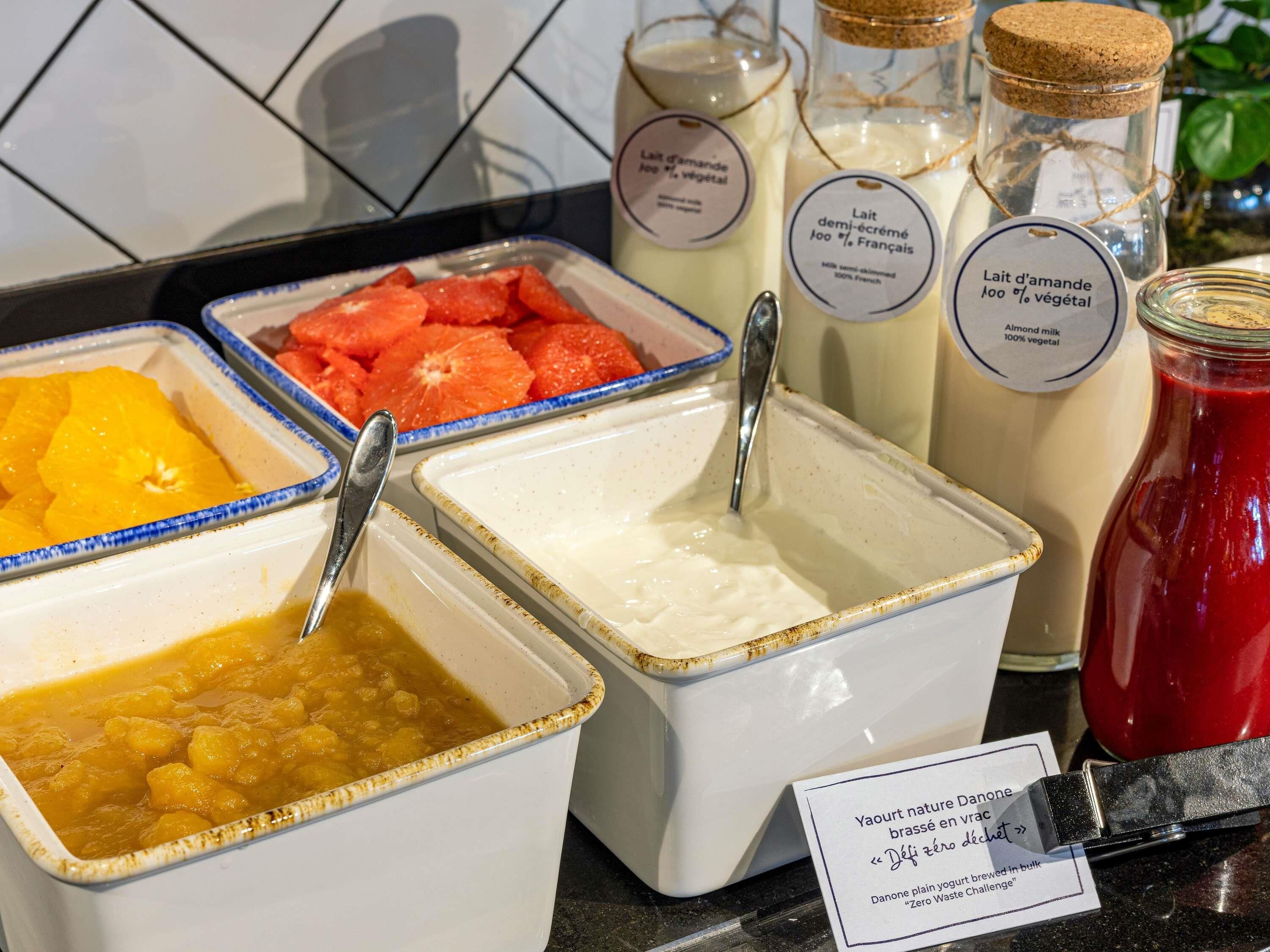 Ein Frühstücksbuffet mit verschiedenen Speisen, darunter Obst, Joghurt und Mandelmilch.