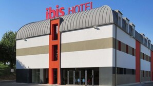 A modern hotel with a distinctive red and white color scheme, a curved roof, and a prominent signage.