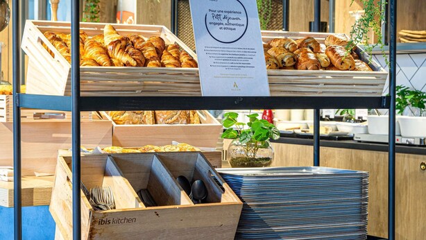 A bakery display with croissants and a sign about a small, authentic experience.