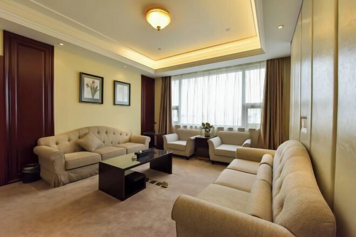 A modern living room with a sofa set, a coffee table, and a large window with curtains.