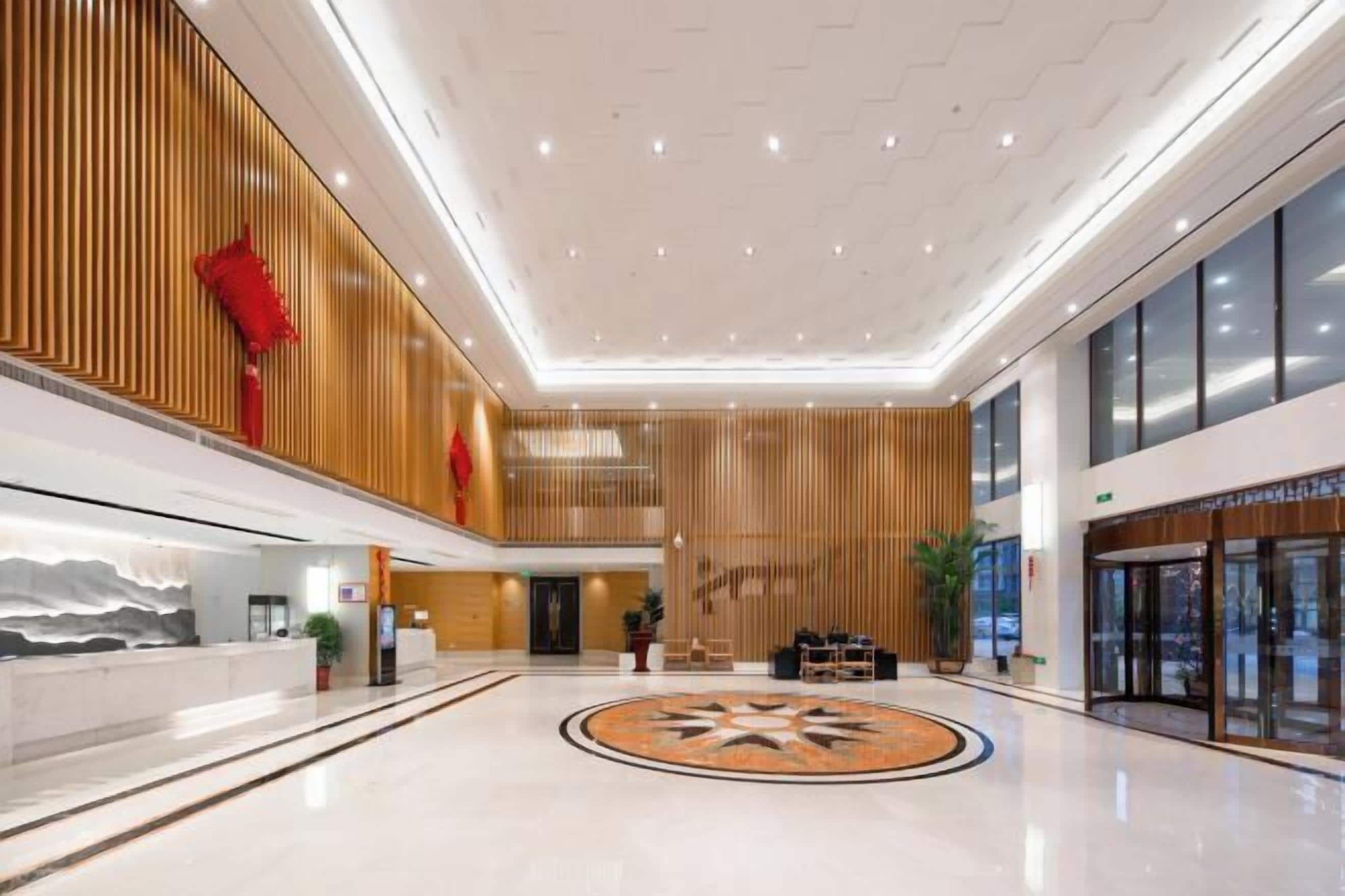 A spacious lobby with a modern design, featuring a reception desk, seating area, and a decorative circular pattern on the floor.