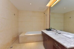 Un baño moderno con bañera, dos lavamanos y un espejo grande.