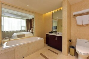 A modern bathroom with a large bathtub, a vanity with a mirror, and a toilet. - Regan International Hotel (Wuxi)