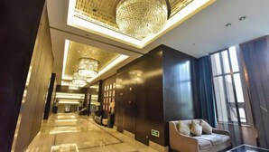 A modern hotel lobby with a long corridor, a sofa, and a chandelier. - Regan International Hotel (Wuxi)