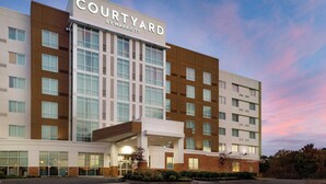 Un hotel Courtyard by Marriott con un diseño moderno, que cuenta con una entrada destacada y varios pisos.