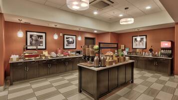 Una cocina de hotel con una isla central, equipada con diversos electrodomésticos y una estación de café.