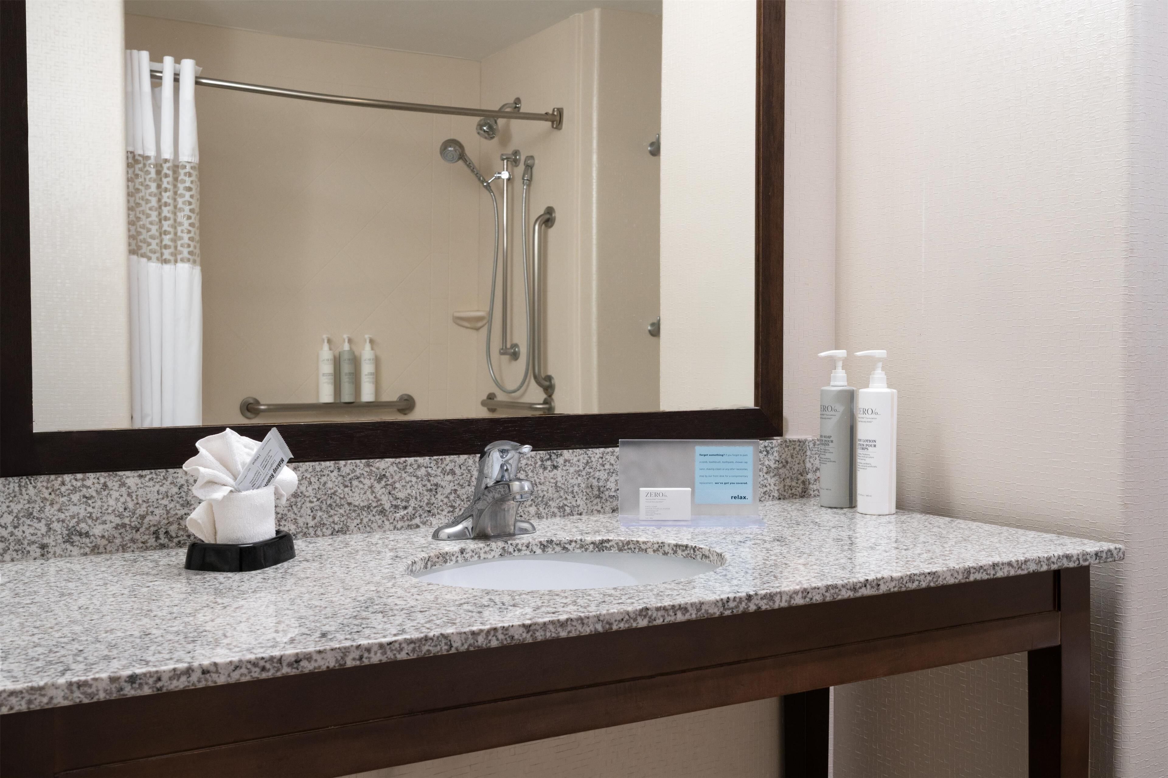 A bathroom with a sink, mirror, and toiletries.
