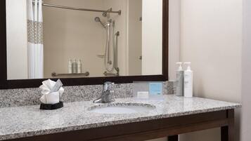 A bathroom with a sink, mirror, and toiletries.