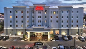 A multi-story hotel with a prominent sign, a parking lot, and a well-lit entrance. - Hampton Inn & Suites Albuquerque North/I-25 (Albuquerque)