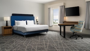 A hotel room with a bed, bedside tables, a desk, a chair, a TV, and a window with curtains. - Hampton Inn & Suites Albuquerque North/I-25 (Albuquerque)