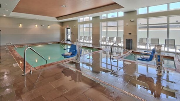 An indoor swimming pool with clear lanes, blue chairs, and a tiled floor. - Hampton Inn & Suites Albuquerque North/I-25 (Albuquerque)