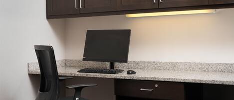 Un escritorio moderno con una computadora, una silla e impresora.