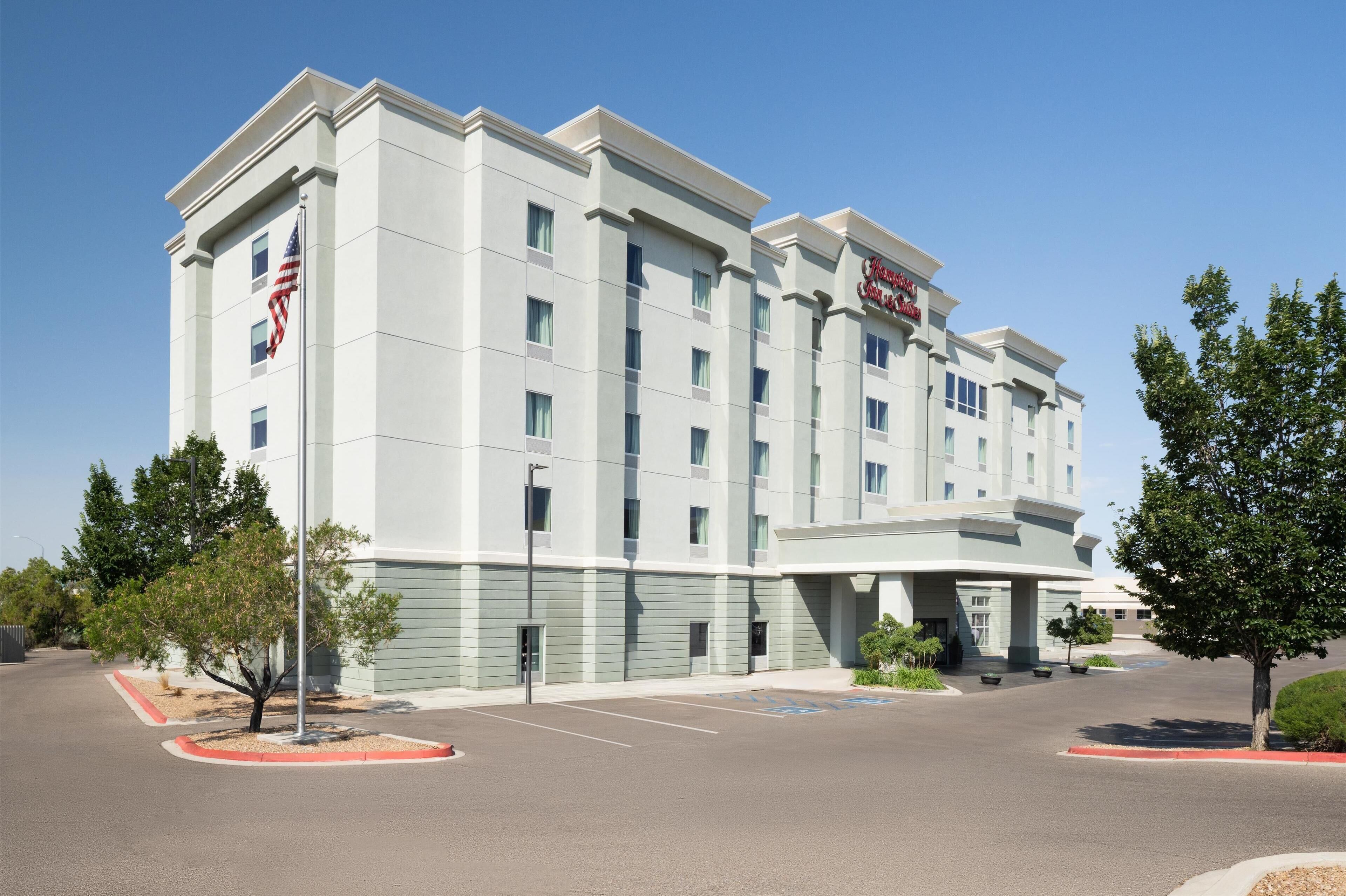 A large, multi-story hotel with a prominent American flag, a sign reading "Marriott Hotel," and a parking lot with a few trees.