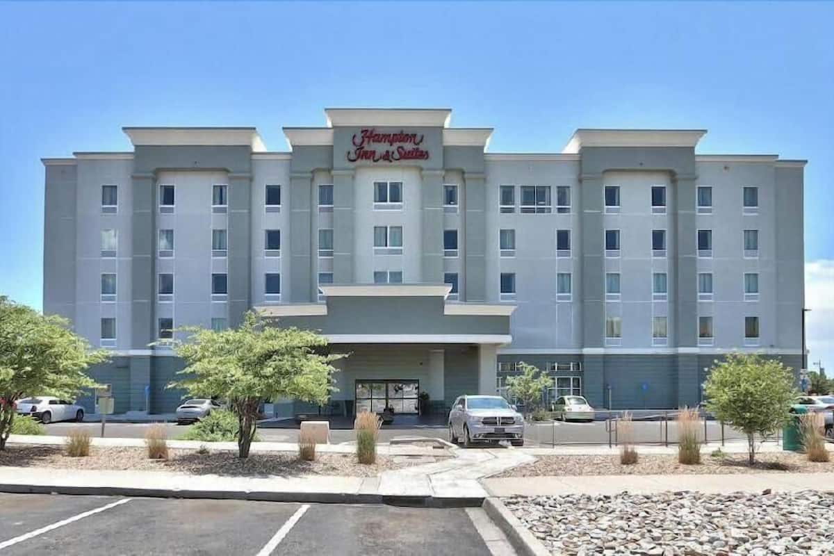 Un edificio de varios pisos con un letrero que dice 'Hampton Inn & Suites'.