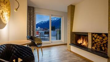 Una sala de estar moderna con chimenea, un comedor con mesa y sillas, y un ventanal con vistas a la montaña.