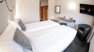 Una habitación de hotel con una cama, un escritorio, una silla, un televisor y un armario.