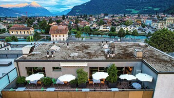 Terraza en la azotea con mobiliario exterior y vistas a un pueblo y montañas.