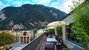 An outdoor terrace with tables and chairs, overlooking a mountainous landscape. - Hotel Merkur Interlaken (Interlaken)