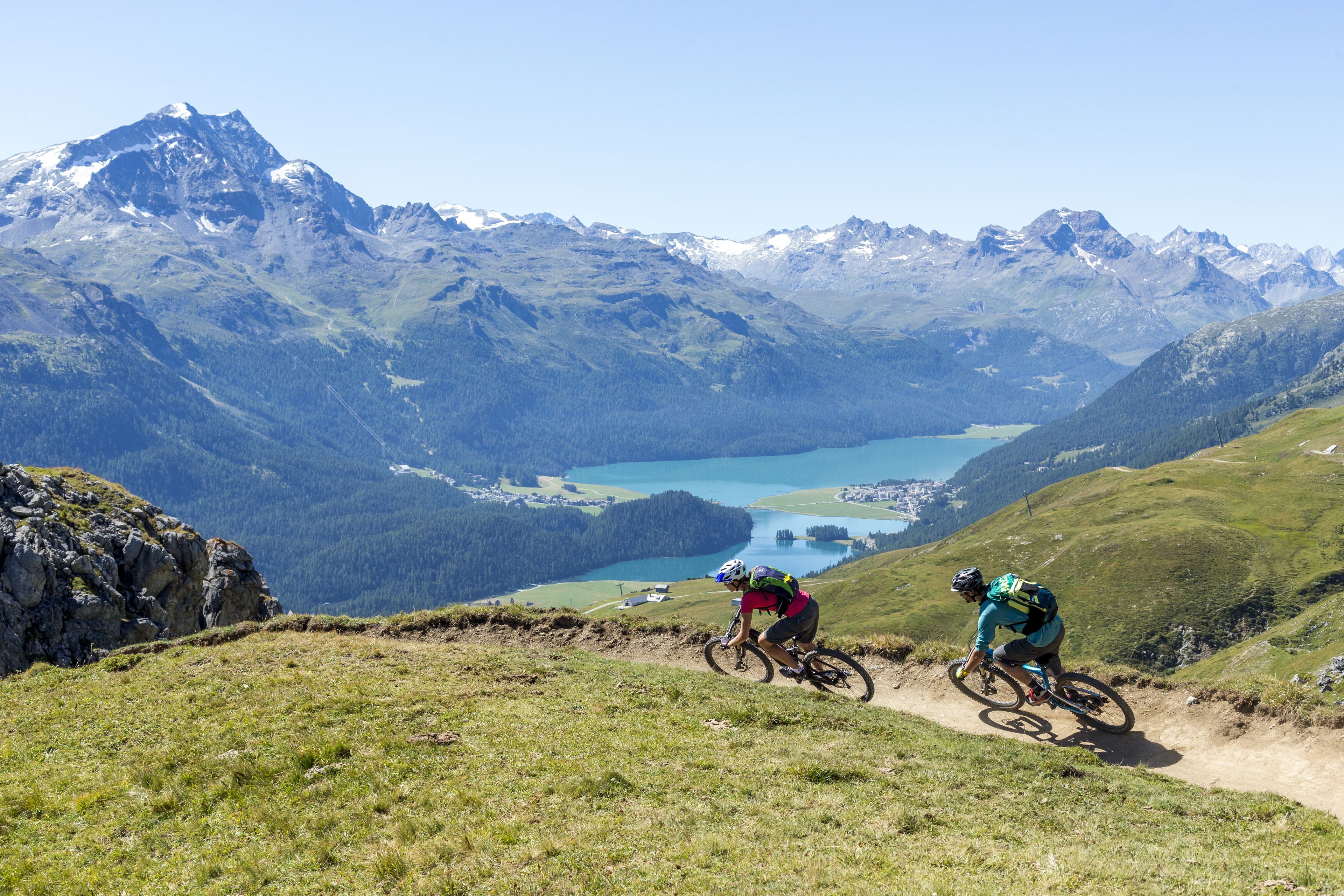 A mountain biking trail with a view of a lake and mountains in the background.