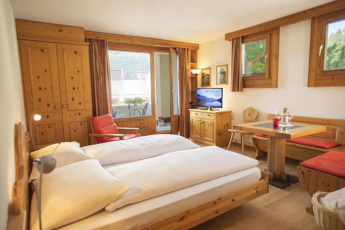 A hotel room with a large bed, wooden furniture, a television, and a view of the outdoors.