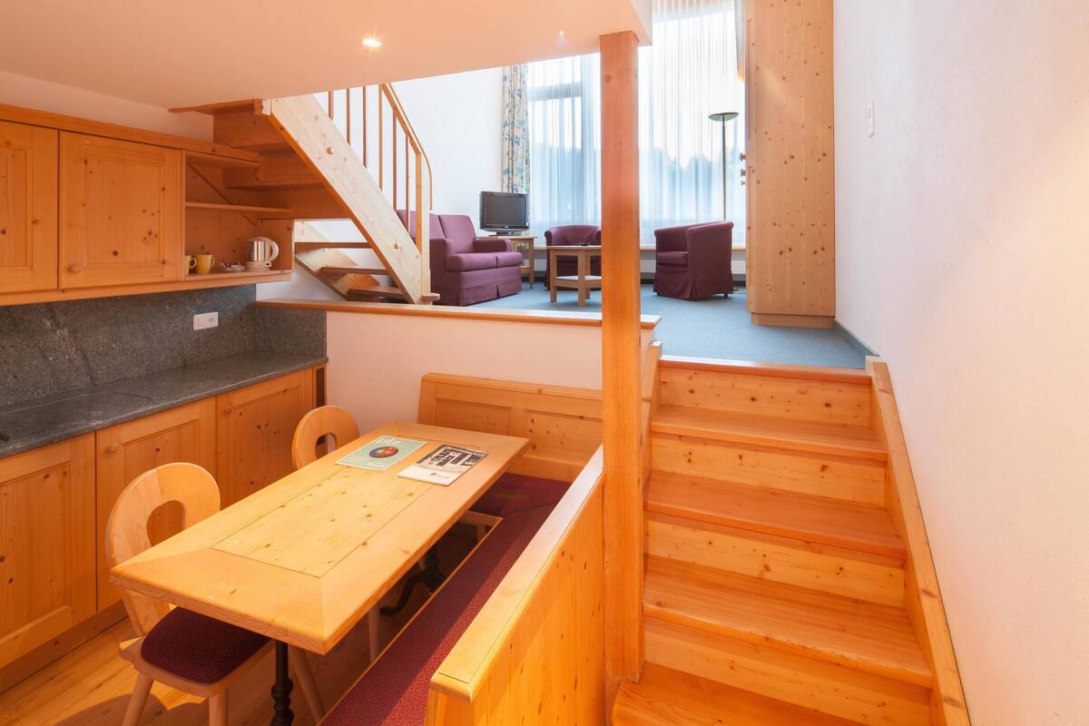 A compact kitchen with wooden cabinets and a dining area with a bench.