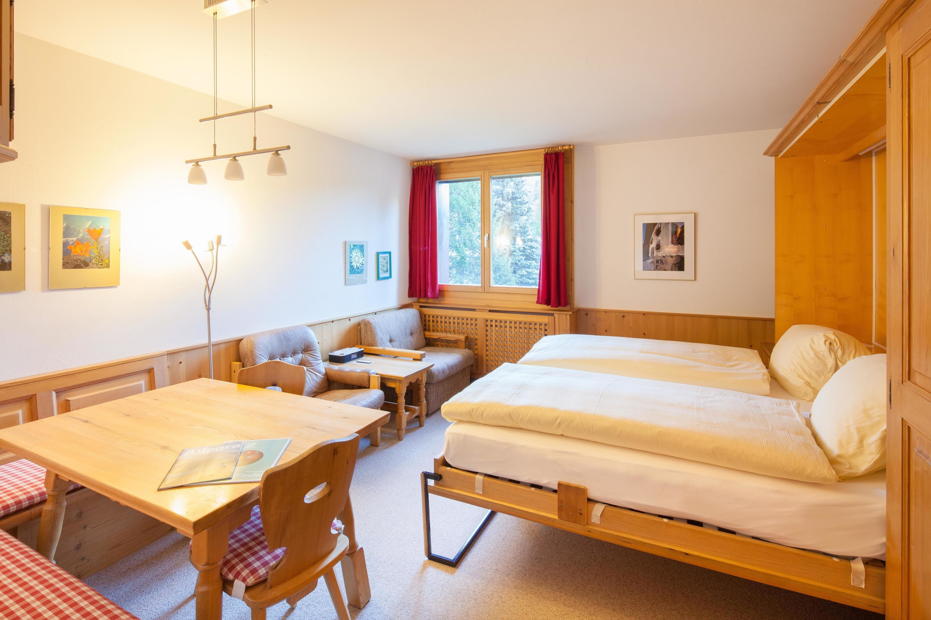 Una habitación acogedora con una cama de madera, una mesita, una silla y un sofá.
