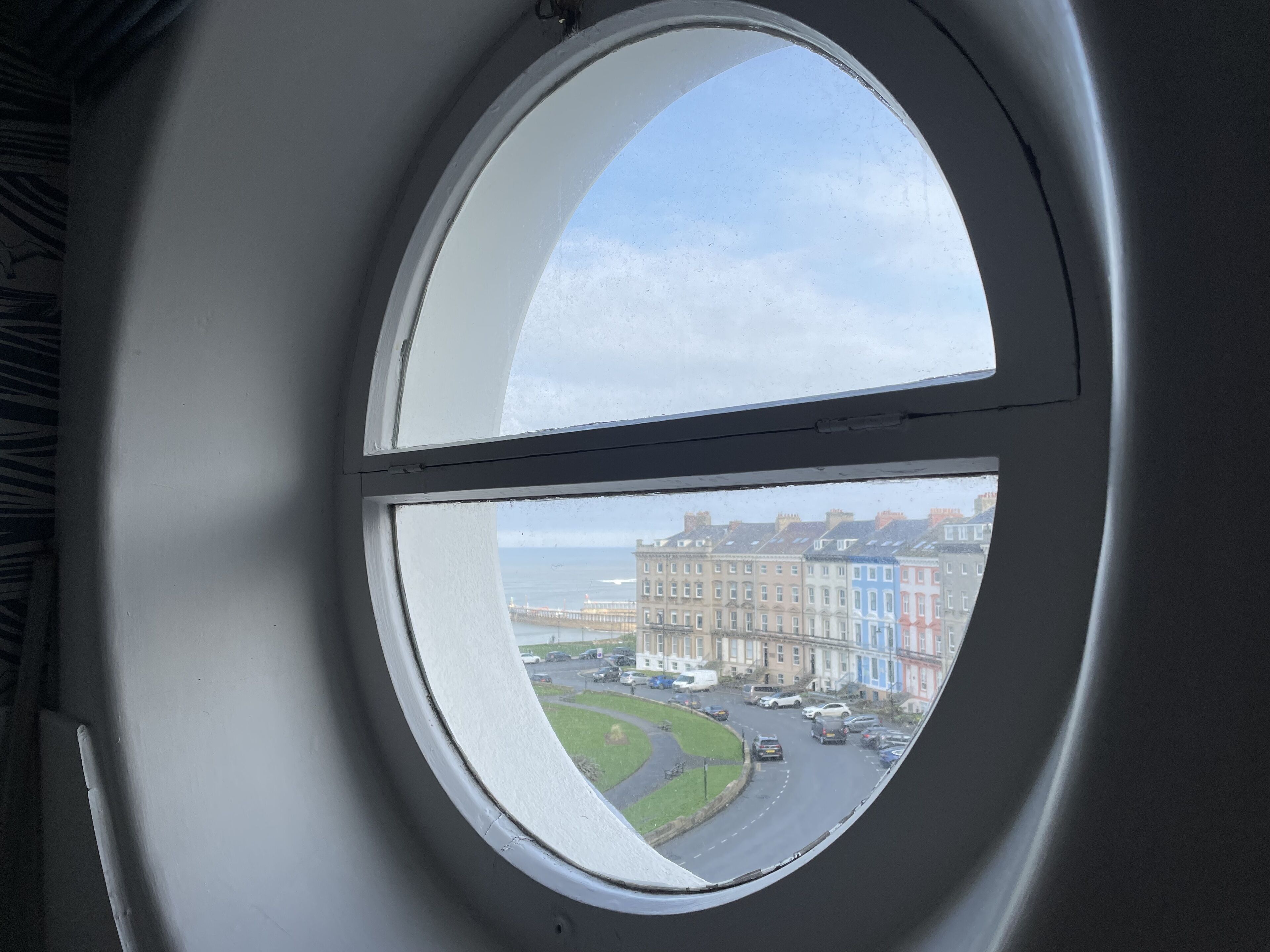 Ein rundes Fenster mit Blick auf eine Straße und Häuser.