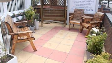A patio area with wooden benches and potted plants.