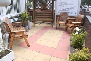 A patio area with wooden benches and potted plants. - Serena Court Hotel (Skegness)