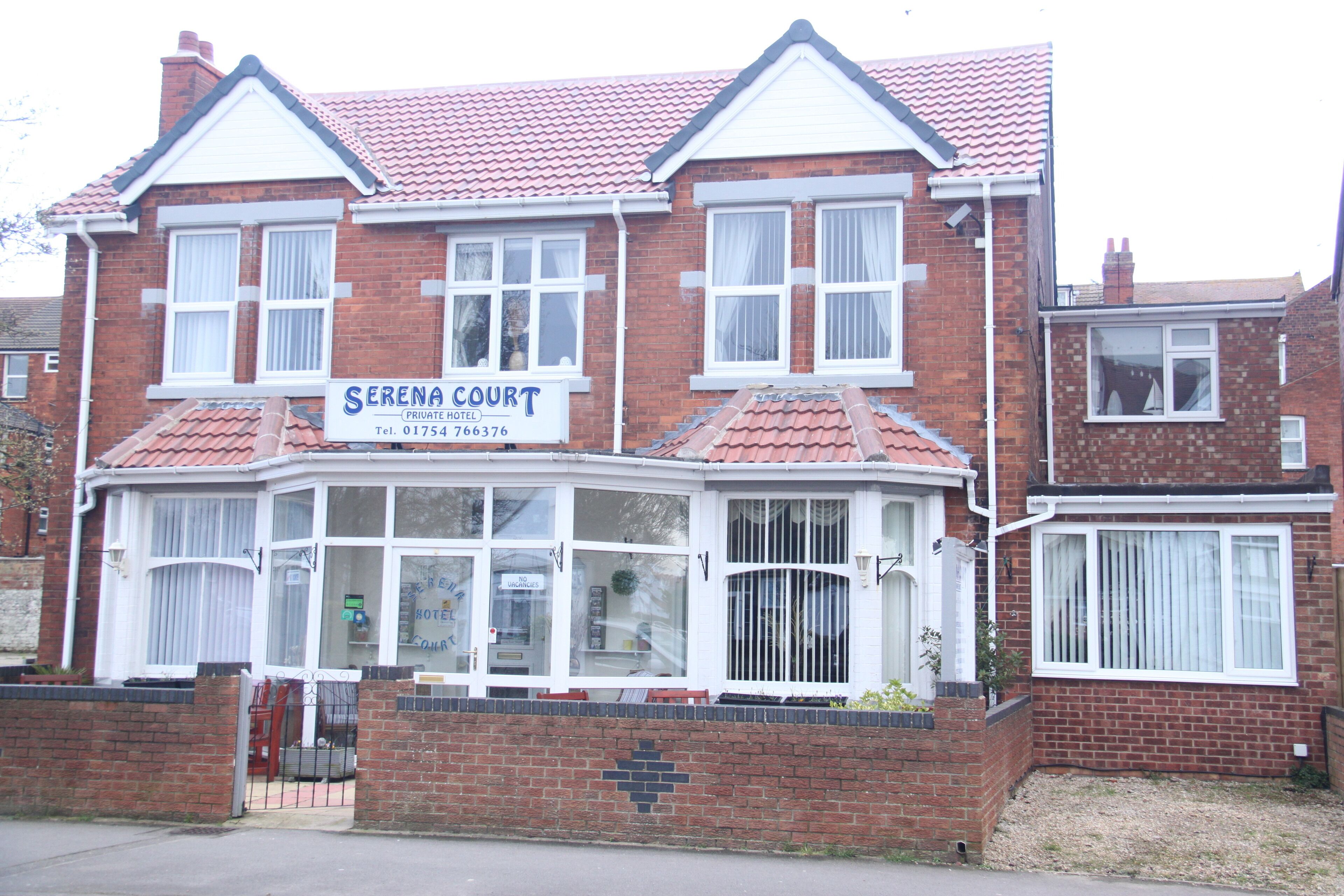 A two-story brick building with a sign for 'Serena Court Private Hotel'.