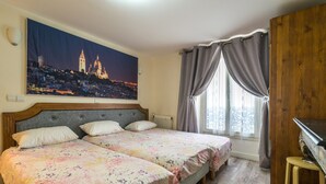Un dormitorio con dos camas, un cuadro de gran tamaño con un paisaje urbano, un cabecero de madera, un radiador, un piano y una ventana con cortinas.