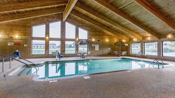 Una piscina interior con vigas de madera, ventanas amplias y zonas de estar.